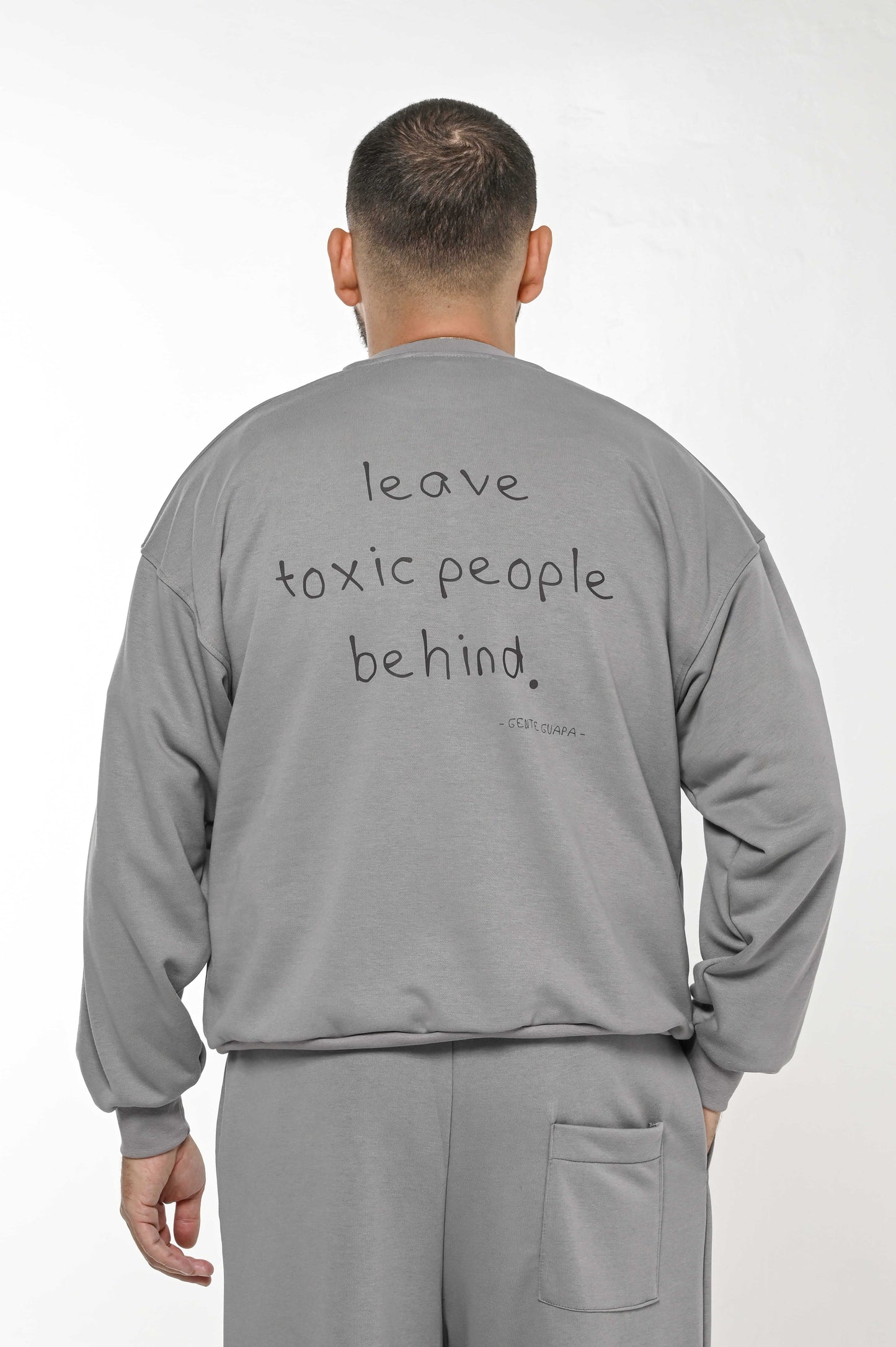 Gente Guapa black hoodie with “Leave toxic people behind” quote — unisex streetwear back view